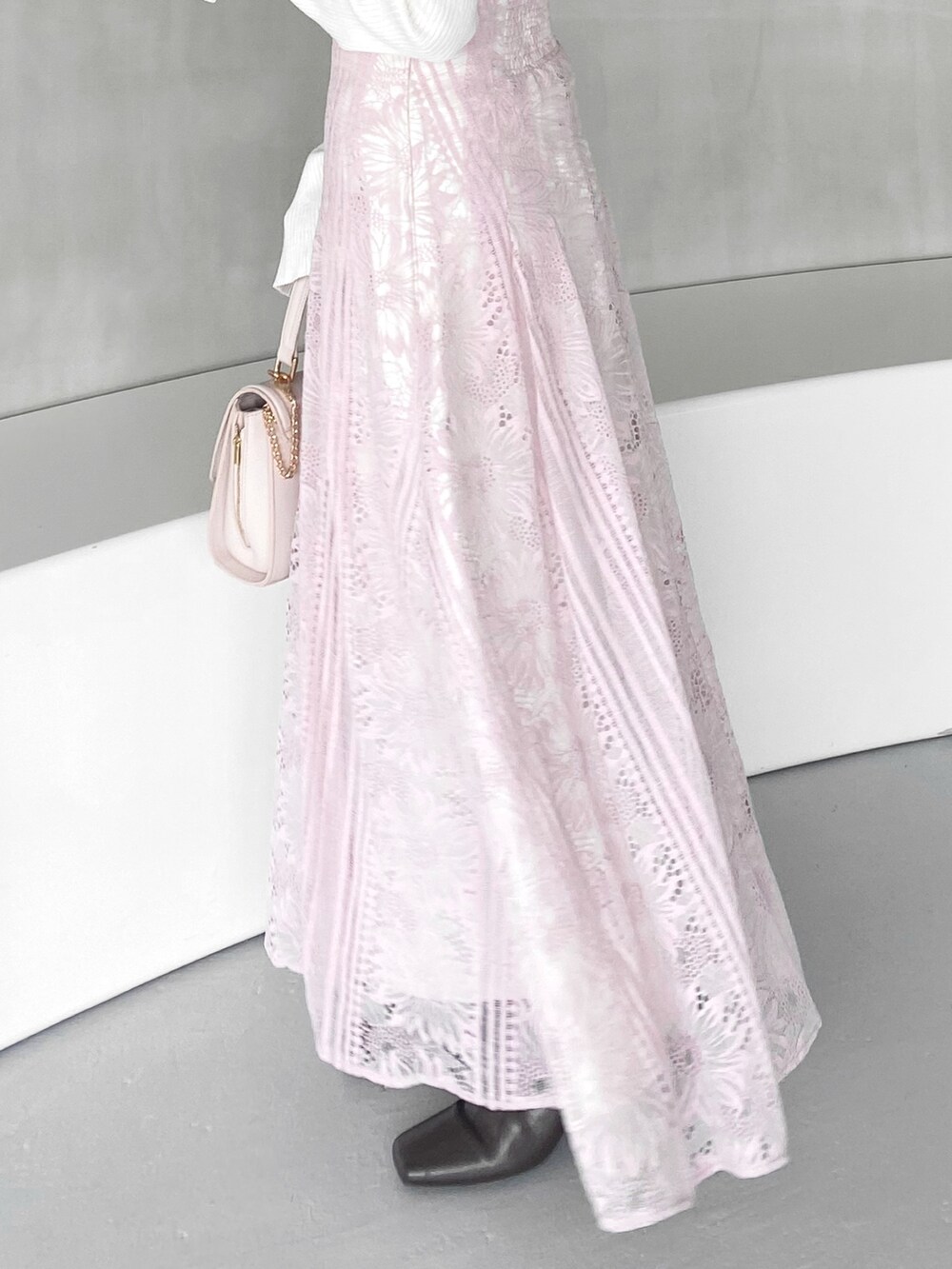 ピンク系のハンドバッグ、ピンク系のスカート、ホワイト系のニット/セーターを着用したレディースの冬コーディネートの4枚目の写真