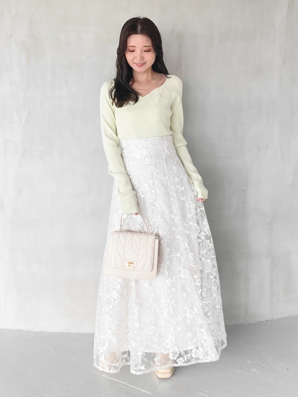 ホワイト系のスカート、ホワイト系のショルダーバッグ、グリーン系のニット/セーターを着用したレディースの秋コーディネートの2枚目の写真
