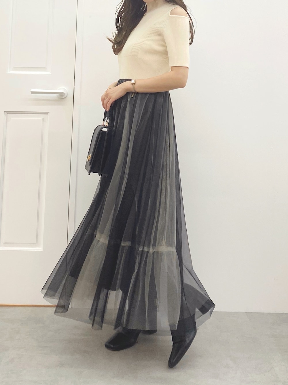 ブラック系のハンドバッグ、ブラック系のブーツ、ホワイト系のワンピースを着用したレディースの夏コーディネートの2枚目の写真