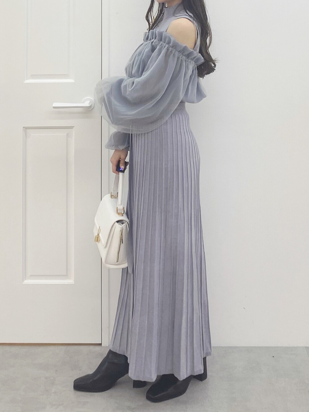 ブラック系のブーツ、ホワイト系のハンドバッグ、ブルー系のワンピースを着用したレディースの秋コーディネートの4枚目の写真