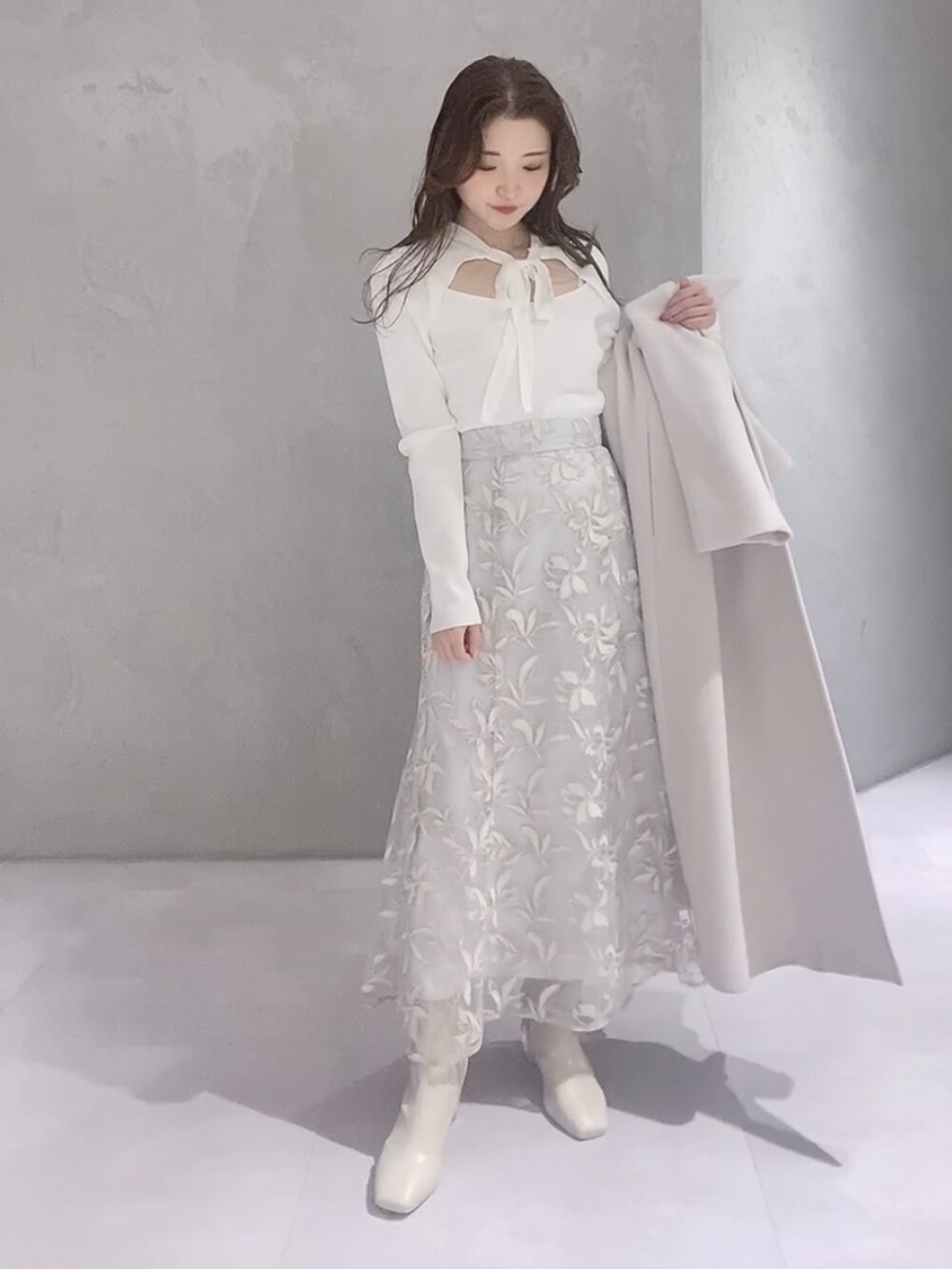 ホワイト系のニット/セーター、ホワイト系のチェスターコート、ブラウン系のハンドバッグを着用したレディースの冬コーディネートの5枚目の写真