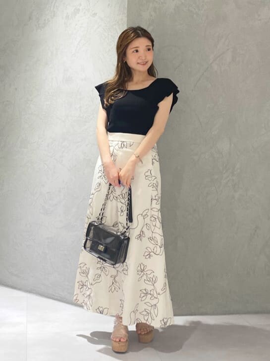 ブラック系のショルダーバッグ、ブラック系のニット/セーター、ホワイト系のスカートを着用したレディースの夏コーディネートの8枚目の写真