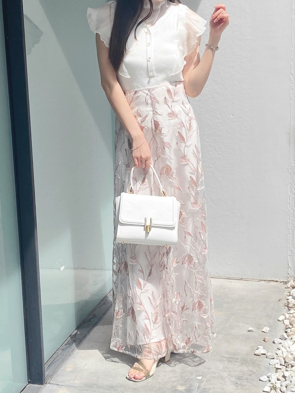 ホワイト系のサンダル、ホワイト系のショルダーバッグ、ピンク系のスカートを着用したレディースの夏コーディネートの2枚目の写真