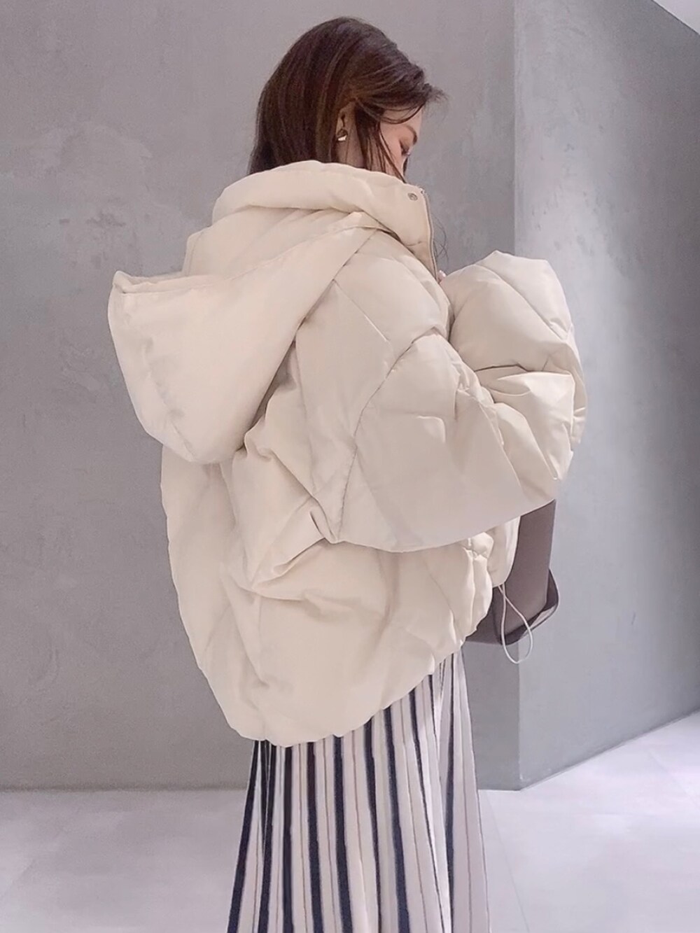 ホワイト系のワンピース、ホワイト系のブーツ、ブラウン系のハンドバッグを着用したレディースの冬コーディネートの4枚目の写真