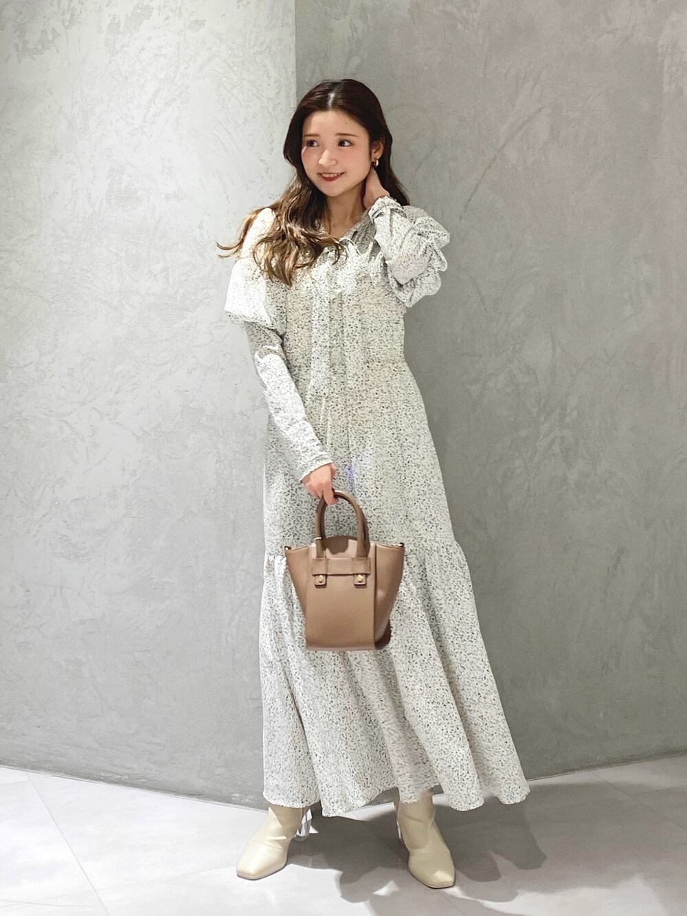 ホワイト系のワンピース、ホワイト系のブーツ、ブラウン系のハンドバッグを着用したレディースの冬コーディネートの3枚目の写真