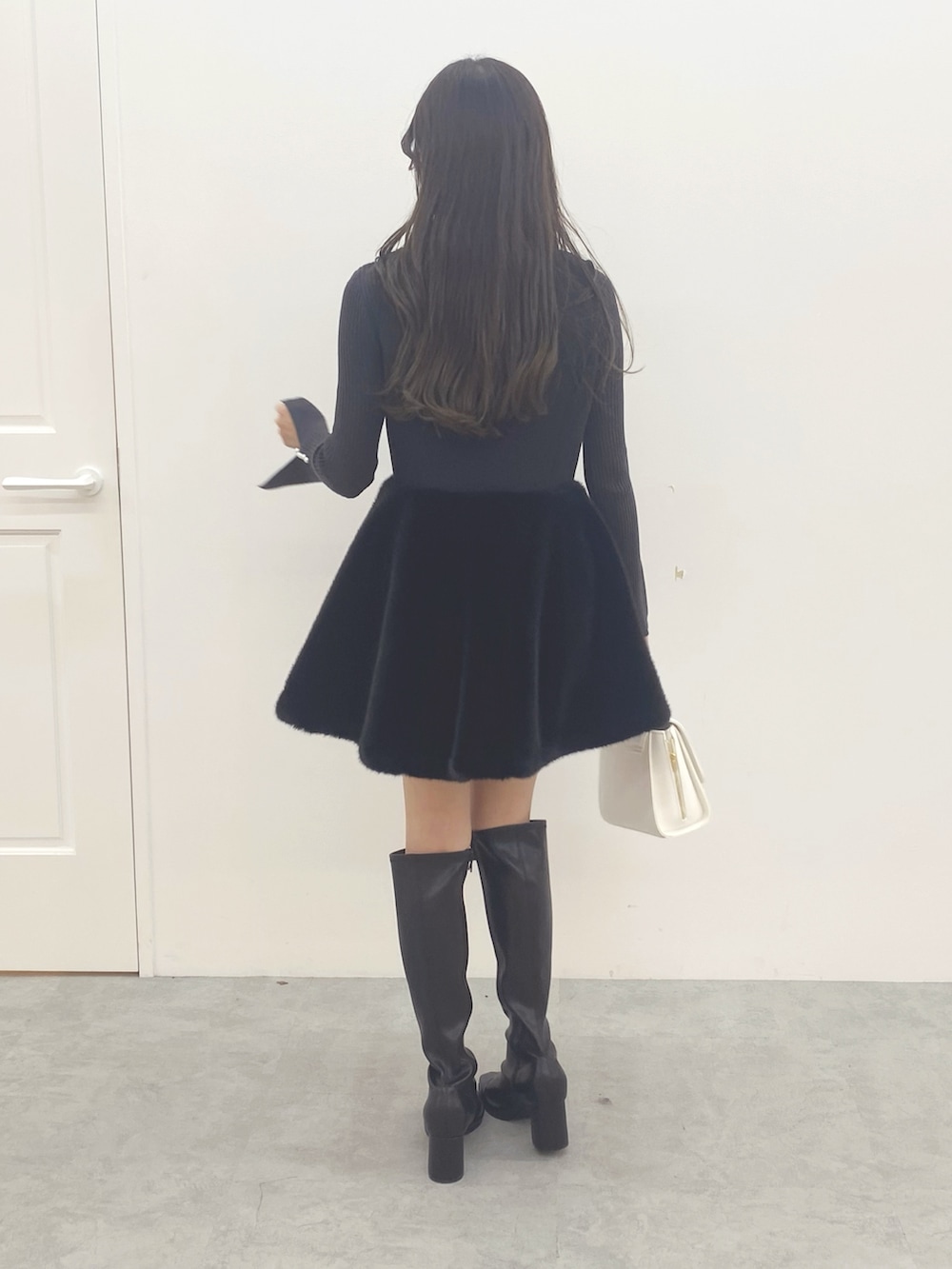 ブラック系のブーツ、ブラック系のワンピース、ホワイト系のハンドバッグを着用したレディースの秋コーディネートの7枚目の写真