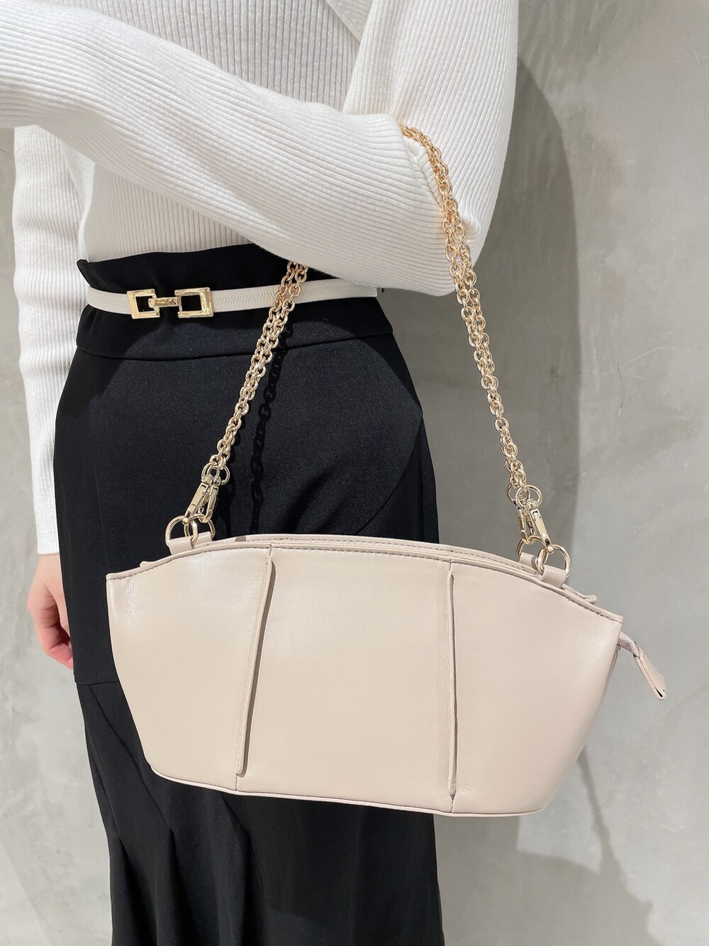 ホワイト系のニット/セーター、ベージュ系のハンドバッグ、ブラック系のスカートを着用したレディースの冬コーディネートの6枚目の写真