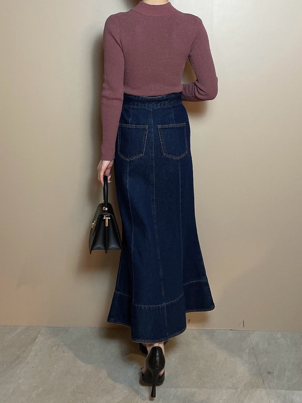 ピンク系のニット/セーター、ブルー系のデニムスカート、ブラック系のパンプスを着用したレディースの冬コーディネートの4枚目の写真