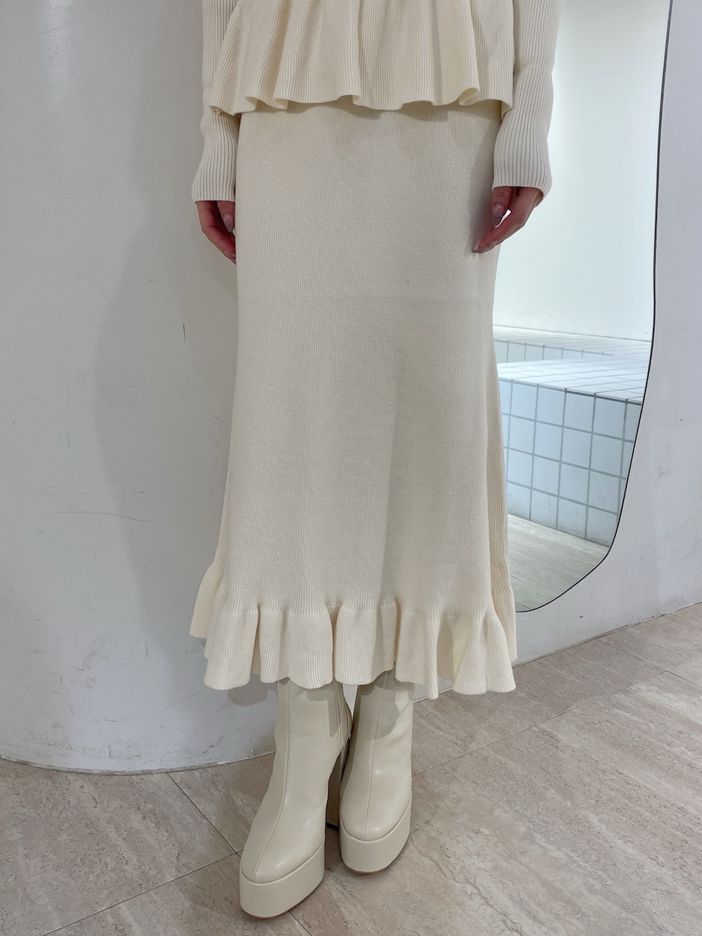 ホワイト系のニット/セーター、ホワイト系のスカート、ホワイト系のブーツを着用したレディースの冬コーディネートの6枚目の写真