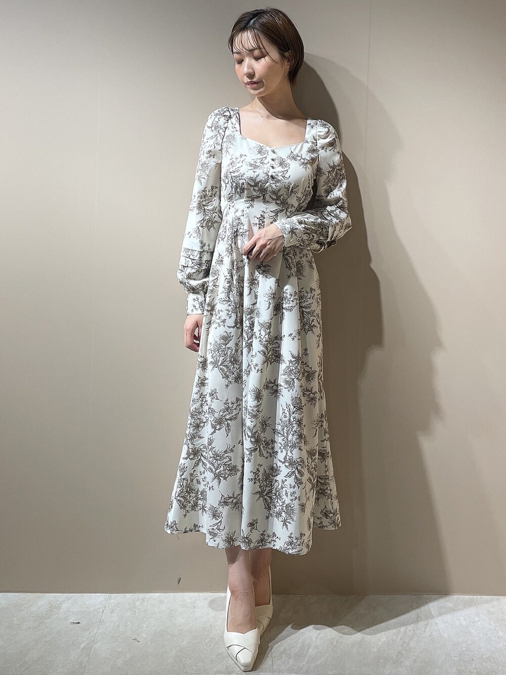 ホワイト系のダウンジャケット/コート、ホワイト系のパンプス、ベージュ系のワンピースを着用したレディースの秋コーディネートの6枚目の写真