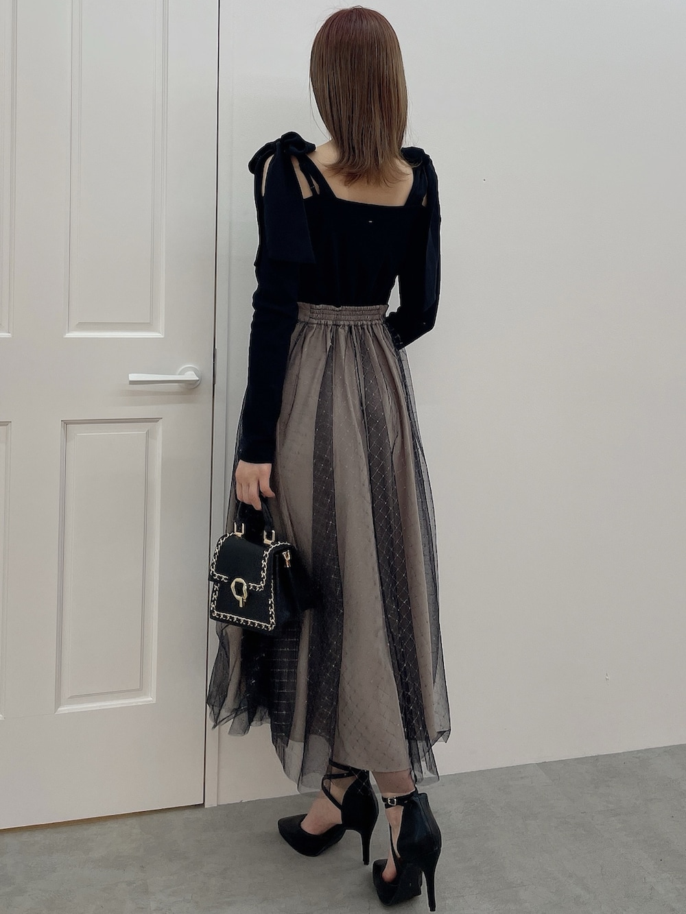 ブラック系のワンピース、ブラック系のハンドバッグ、ブラック系のパンプスを着用したレディースの冬コーディネートの5枚目の写真