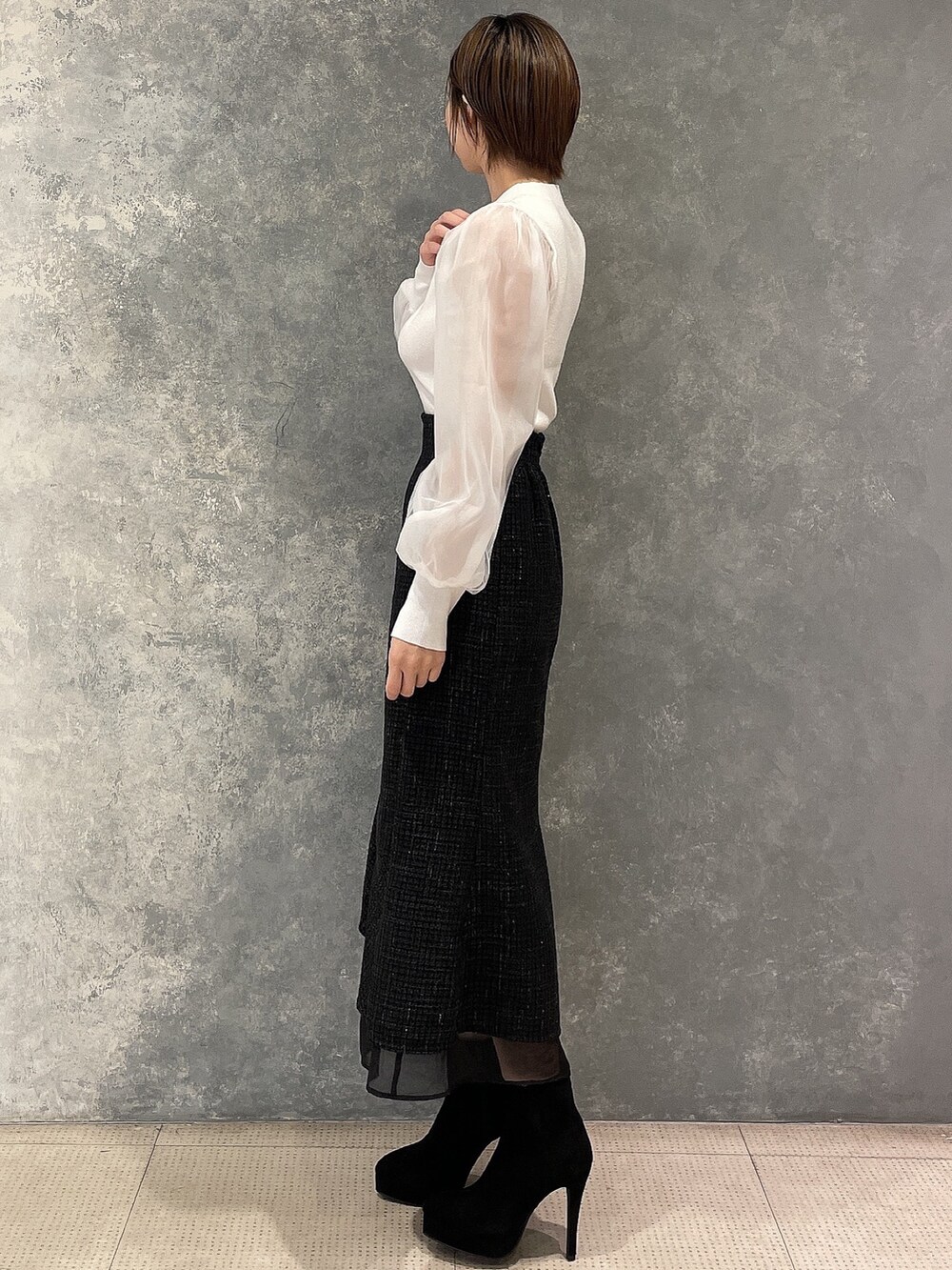 ホワイト系のダウンジャケット/コート、ブラック系のスカート、ブラック系のブーツを着用したレディースの秋コーディネートの7枚目の写真