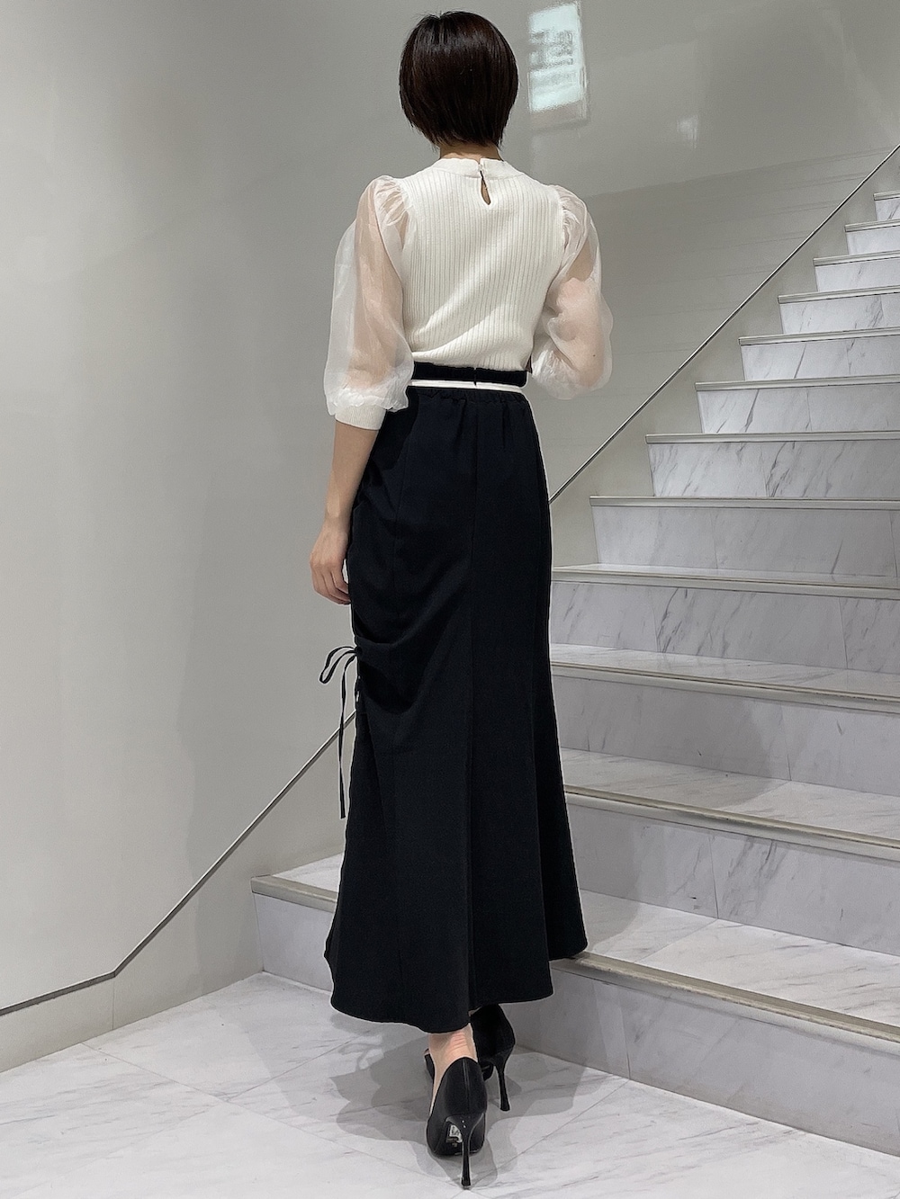 ホワイト系のニット/セーター、ブラック系のスカート、ブラック系のパンプスを着用したレディースの春コーディネートの3枚目の写真