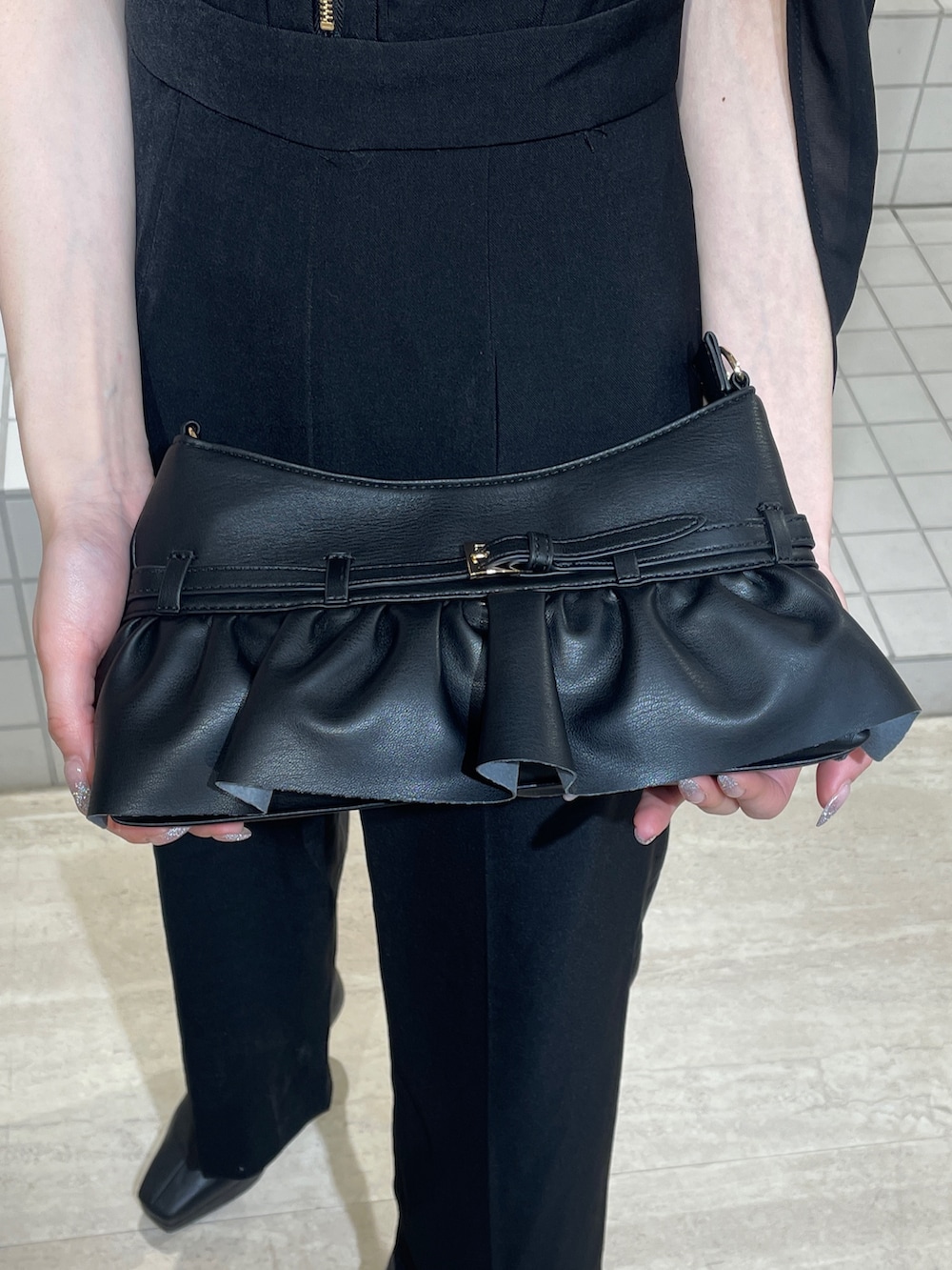 ブラック系のワンピース、ブラック系のブーツ、ブラック系のハンドバッグを着用したレディースの冬コーディネートの8枚目の写真