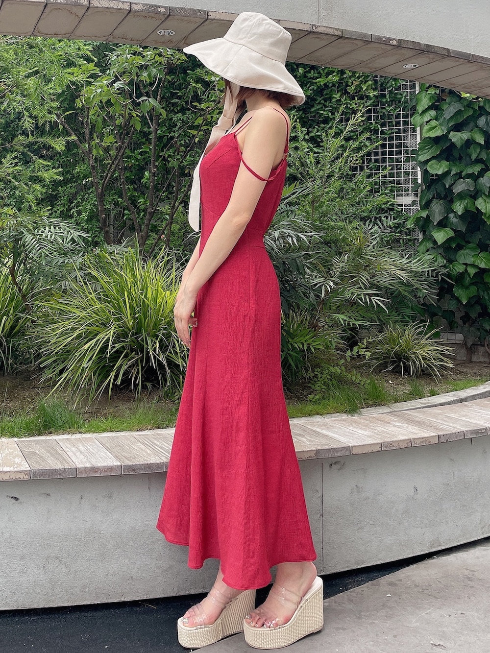 レッド系のワンピース、ホワイト系のサンダル、ホワイト系のハットを着用したレディースの夏コーディネートの3枚目の写真