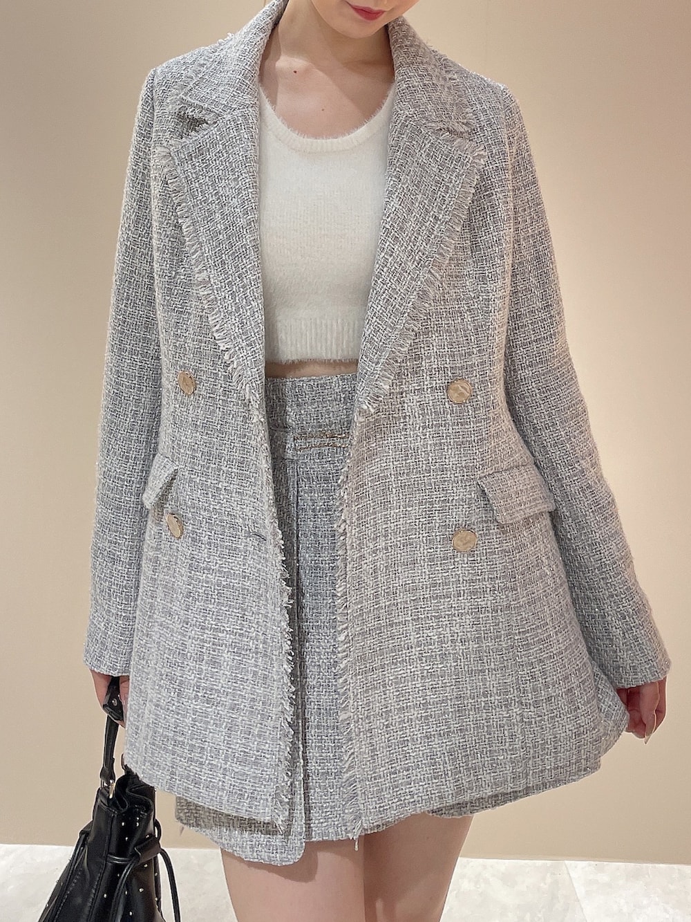 グレー系のテーラードジャケット、グレー系のスカート、ホワイト系のニット/セーターを着用したレディースの秋コーディネートの5枚目の写真