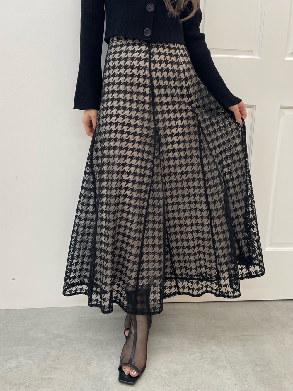 ブラック系のニット/セーター、ブラック系のスカート、ブラック系のブーツを着用したレディースの秋コーディネートの5枚目の写真