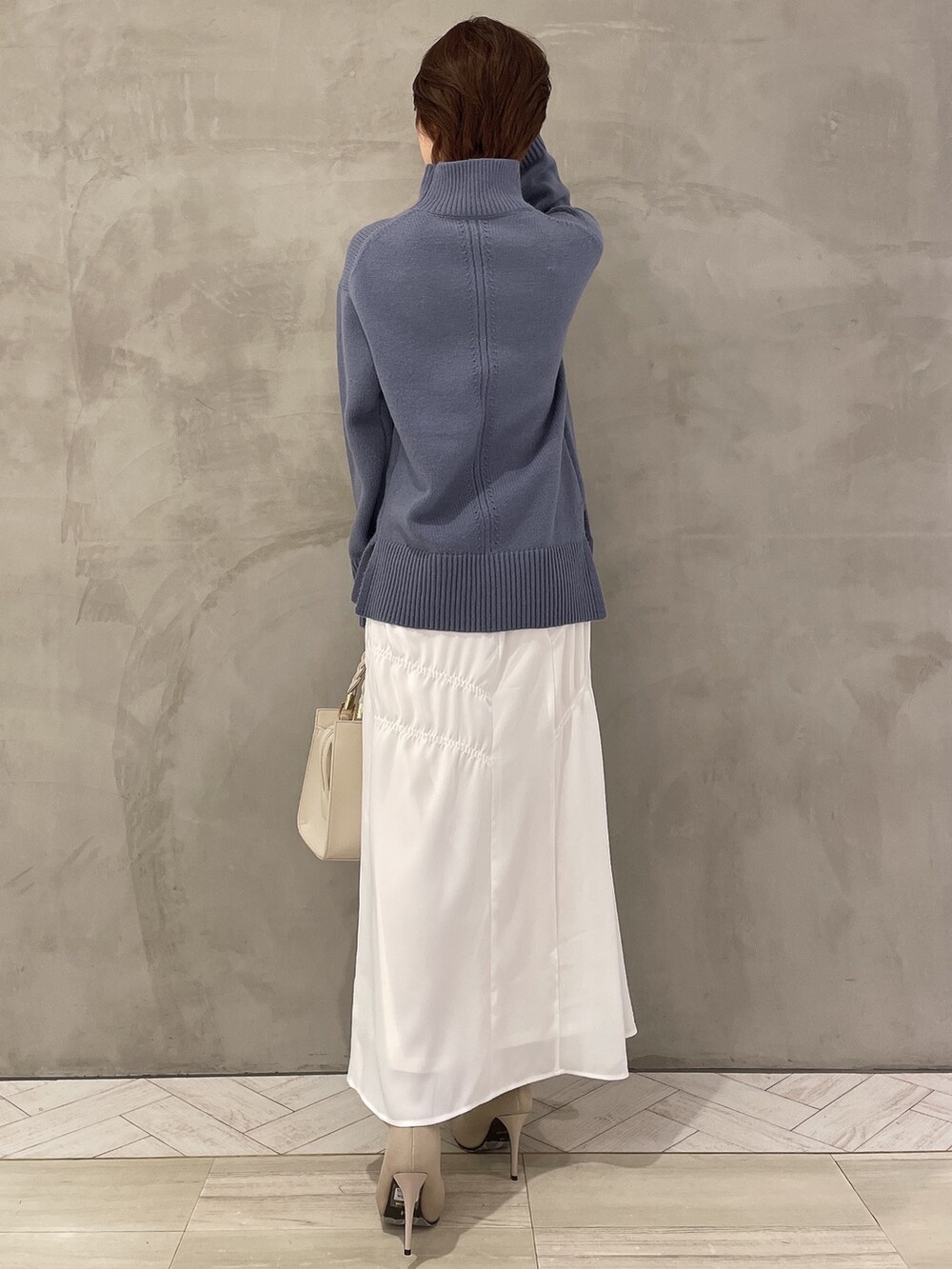 ホワイト系のブーツ、ホワイト系のハンドバッグ、ブルー系のニット/セーターを着用したレディースの冬コーディネートの4枚目の写真