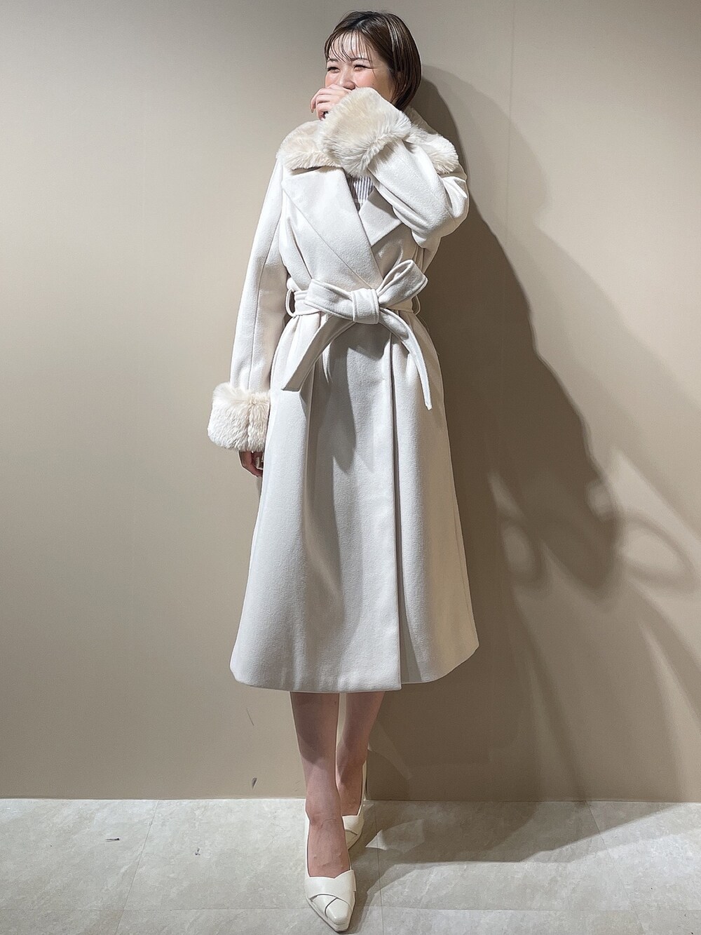 グレー系のワンピース、ホワイト系のパンプス、ホワイト系のチェスターコートを着用したレディースの秋コーディネートの2枚目の写真