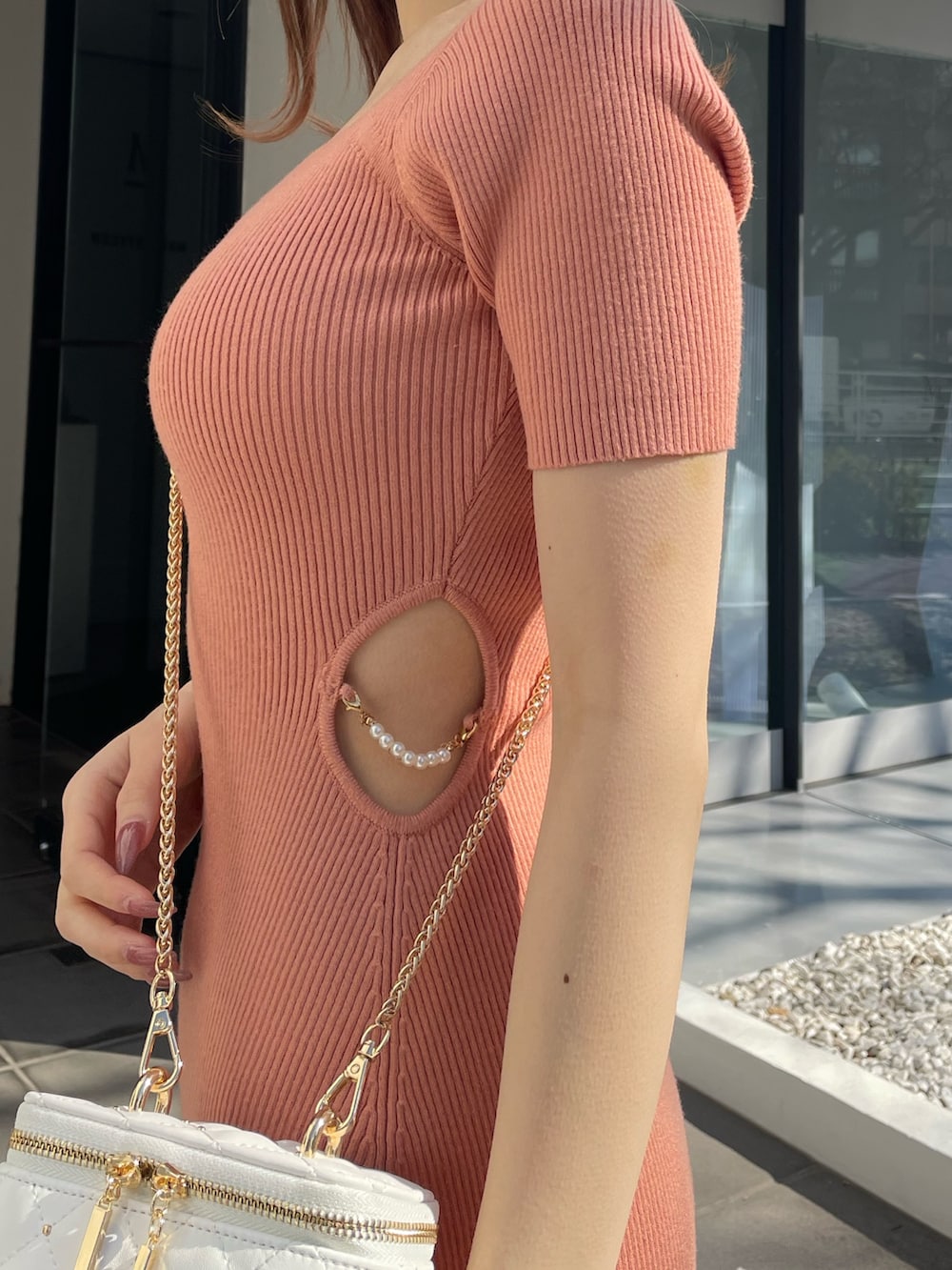 オレンジ系のワンピース、ホワイト系のショルダーバッグ、ホワイト系のパンプスを着用したレディースの冬コーディネートの4枚目の写真