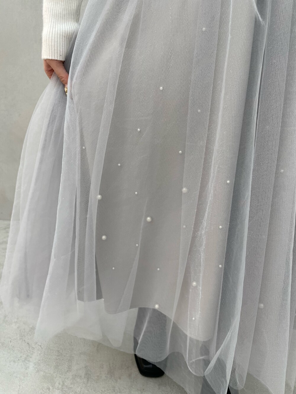 ホワイト系のニット/セーター、グレー系のスカート、ブラック系のブーツを着用したレディースの冬コーディネートの7枚目の写真