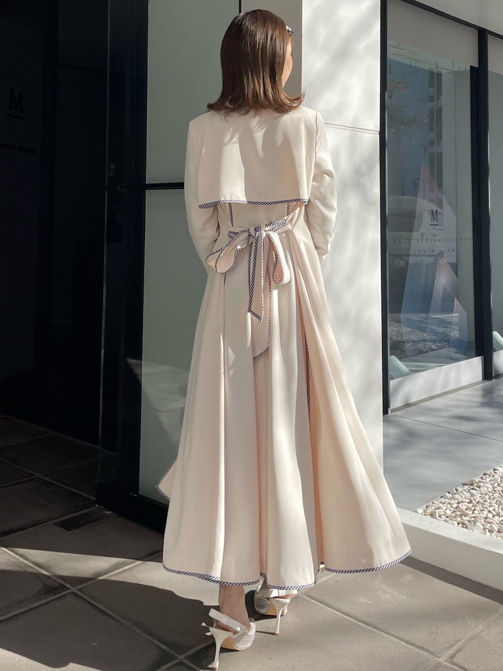 ホワイト系のトレンチコート、ブルー系のワンピース、ホワイト系のパンプスを着用したレディースの冬コーディネートの7枚目の写真