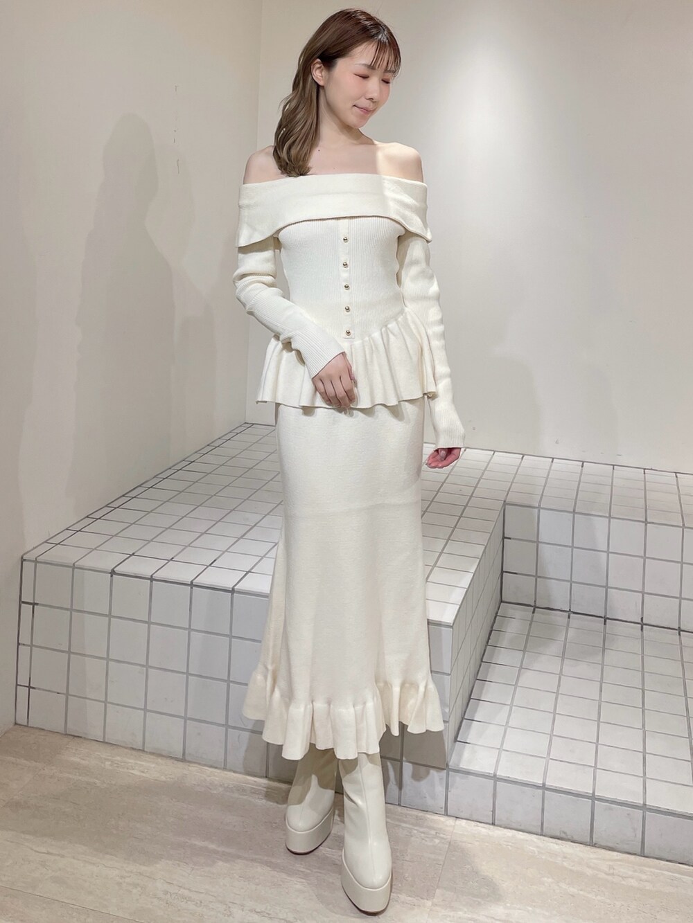 ホワイト系のニット/セーター、ホワイト系のスカート、ホワイト系のブーツを着用したレディースの冬コーディネートの2枚目の写真