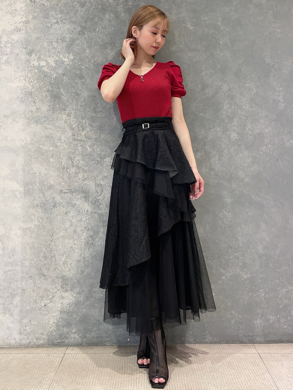 レッド系のニット/セーター、ブラック系のデニムスカート、ブラック系のブーツを着用したレディースの夏コーディネートの2枚目の写真