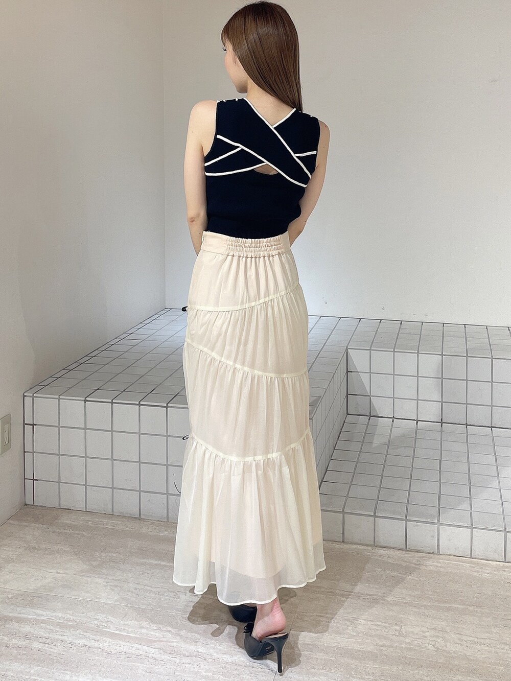 ブラック系のパンプス、ホワイト系のスカート、ブラック系のタンクトップを着用したレディースの夏コーディネートの4枚目の写真