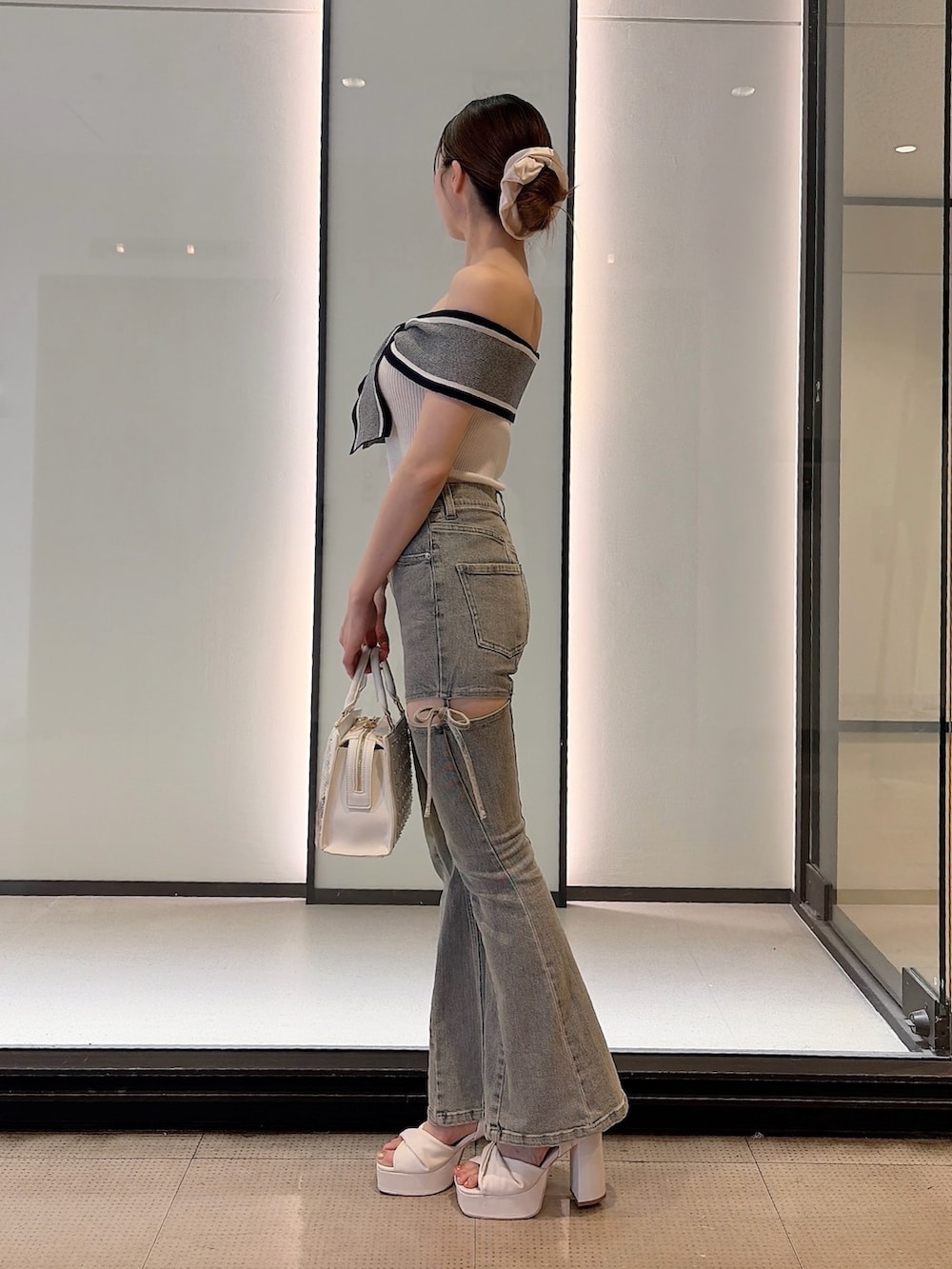 ホワイト系のニット/セーター、ブルー系のデニムパンツ、ホワイト系のハンドバッグを着用したレディースの夏コーディネートの3枚目の写真