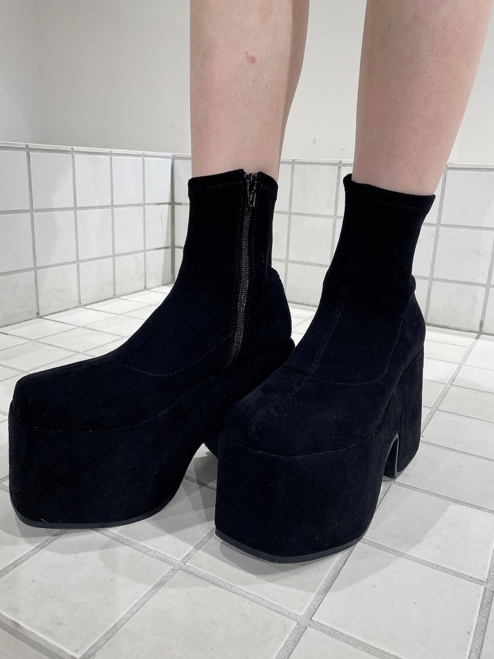 レッド系のニット/セーター、ブラック系のスカート、ブラック系のブーツを着用したレディースの冬コーディネートの7枚目の写真