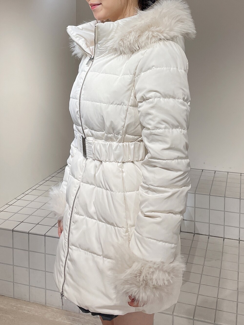 ホワイト系のダウンジャケット/コート、グレー系のワンピース、ブラック系のブーツを着用したレディースの秋コーディネートの5枚目の写真