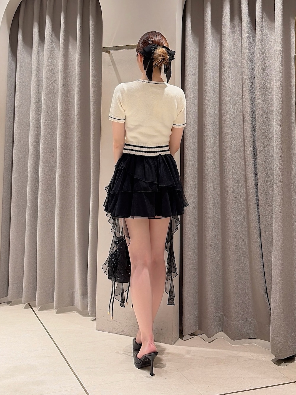 ホワイト系のニット/セーター、ブラック系のスカート、ブラック系のハンドバッグを着用したレディースの夏コーディネートの4枚目の写真