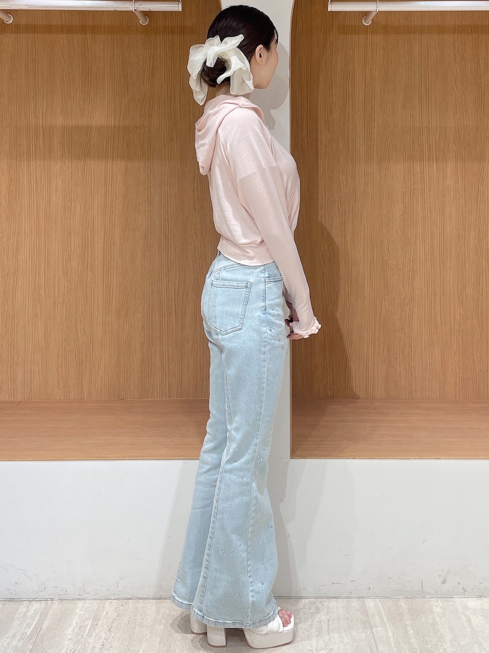 ピンク系のパーカー、ブルー系のデニムパンツ、ホワイト系のサンダルを着用したレディースの春コーディネートの2枚目の写真