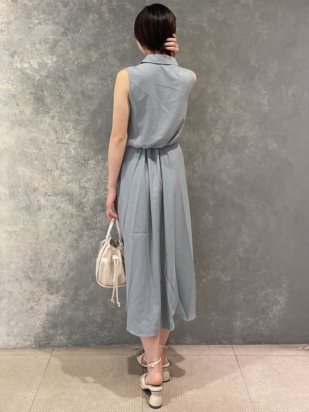 ホワイト系のハンドバッグ、ホワイト系のサンダル、ブルー系のシャツワンピースを着用したレディースの夏コーディネートの3枚目の写真