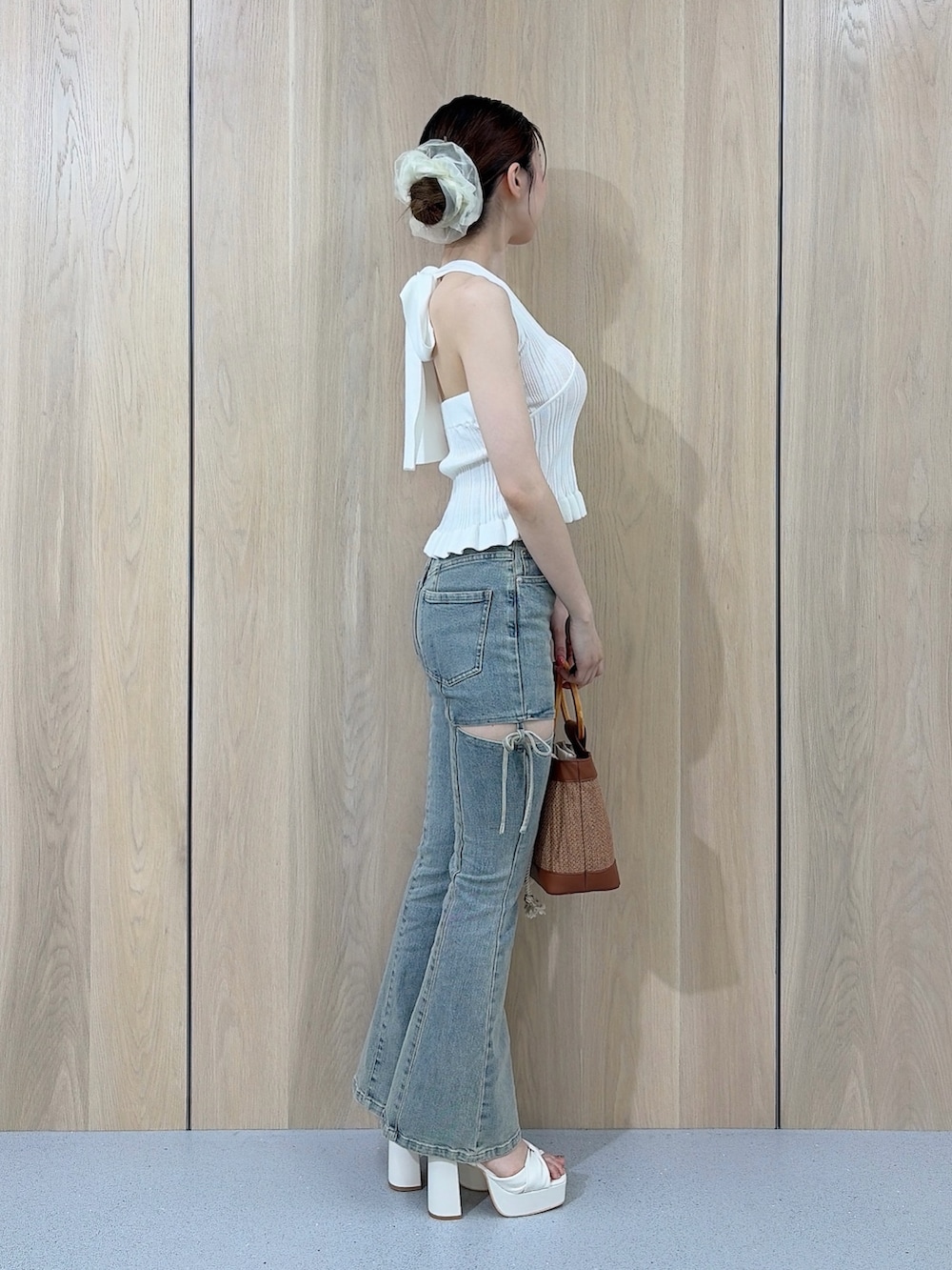 ホワイト系のニット/セーター、ブルー系のデニムパンツ、ブラウン系のハンドバッグを着用したレディースの夏コーディネートの2枚目の写真