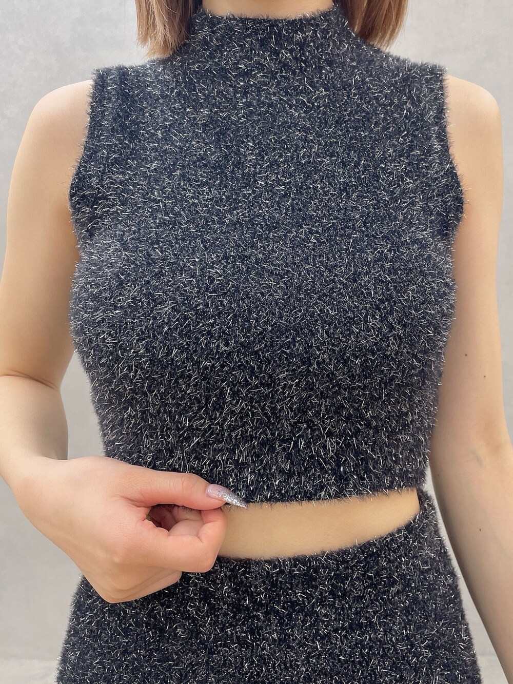 ブラック系のニット/セーター、ブラック系のスカート、ホワイト系のパンプスを着用したレディースの夏コーディネートの6枚目の写真