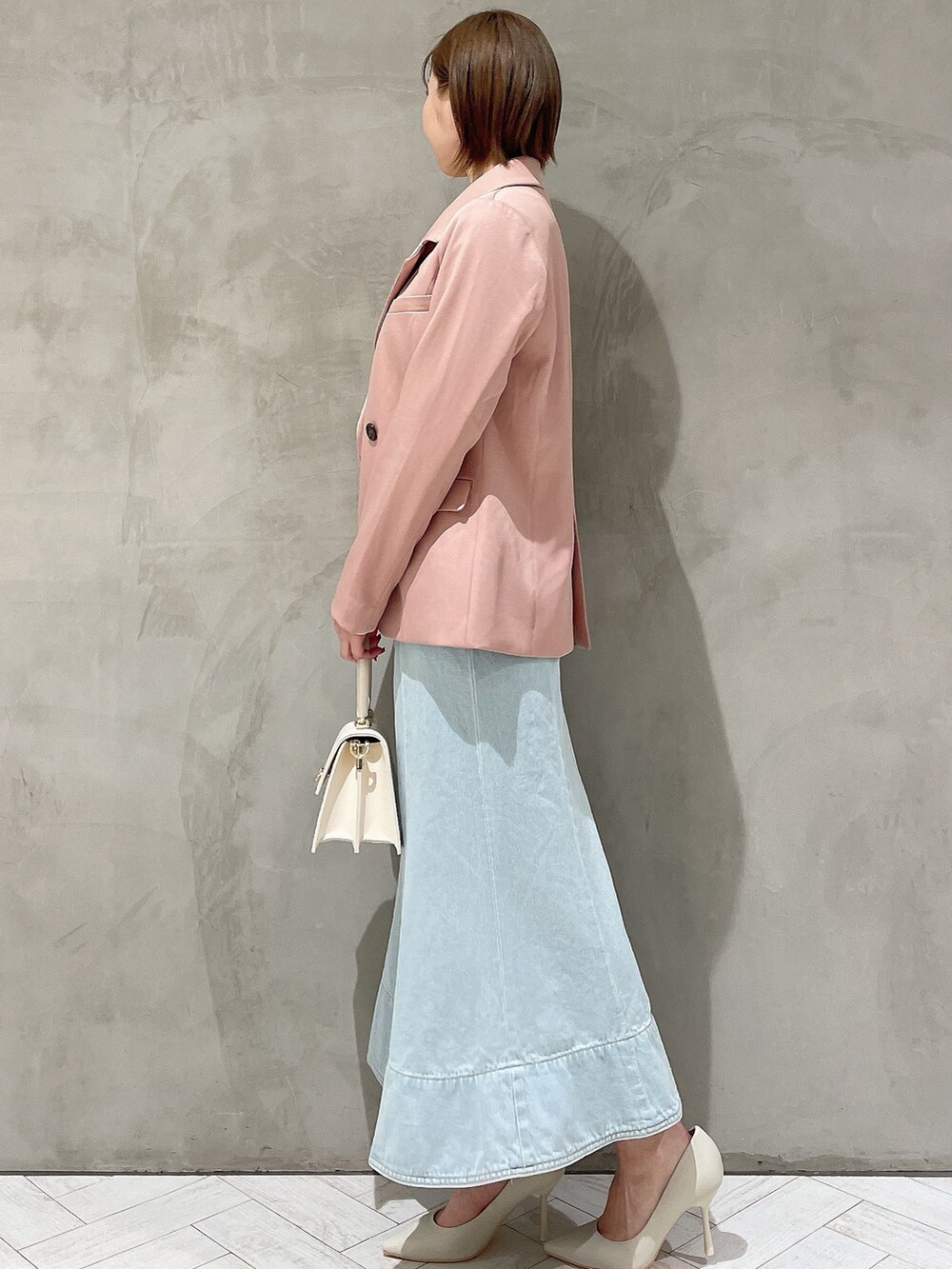 ホワイト系のハンドバッグ、ホワイト系のパンプス、ブルー系のデニムスカートを着用したレディースの冬コーディネートの5枚目の写真