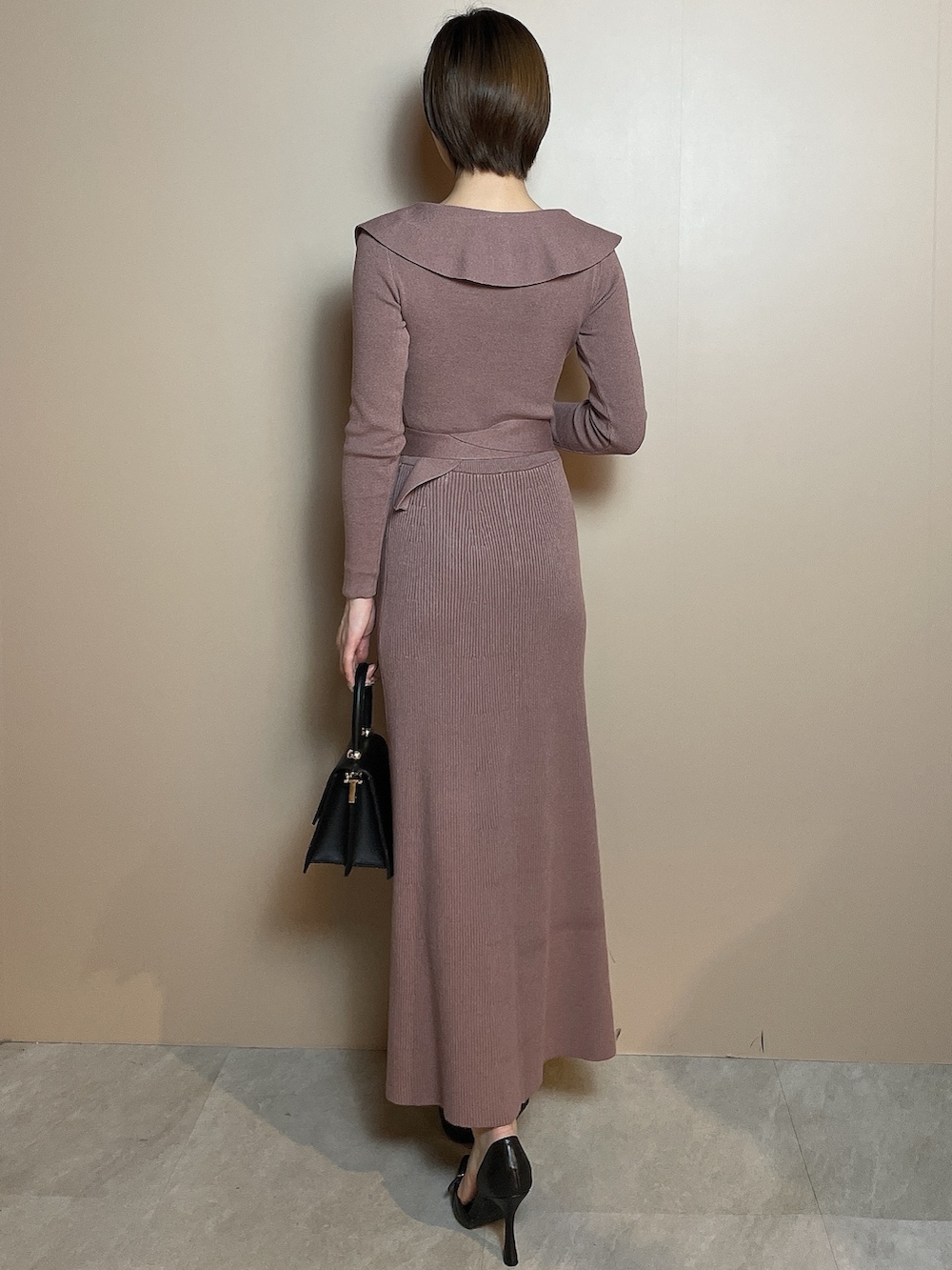 ピンク系のワンピース、ブラック系のハンドバッグ、ブラック系のパンプスを着用したレディースの冬コーディネートの5枚目の写真