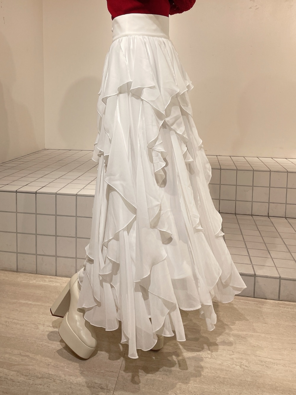 ブルー系のテーラードジャケット、レッド系のニット/セーター、ホワイト系のスカートを着用したレディースの冬コーディネートの9枚目の写真