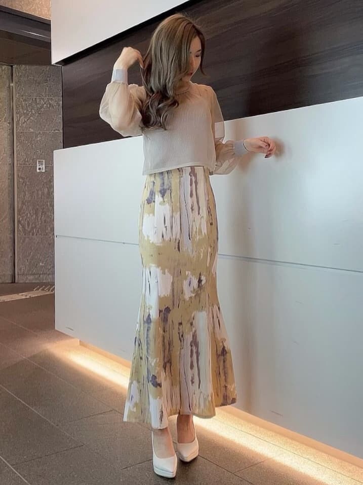 ベージュ系のライダースジャケット、パープル系のスカート、ホワイト系のパンプスを着用したレディースの冬コーディネートの5枚目の写真