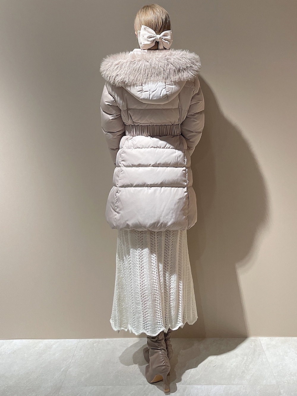 ベージュ系のブーツ、ベージュ系のダウンジャケット/コート、ホワイト系のワンピースを着用したレディースの秋コーディネートの6枚目の写真