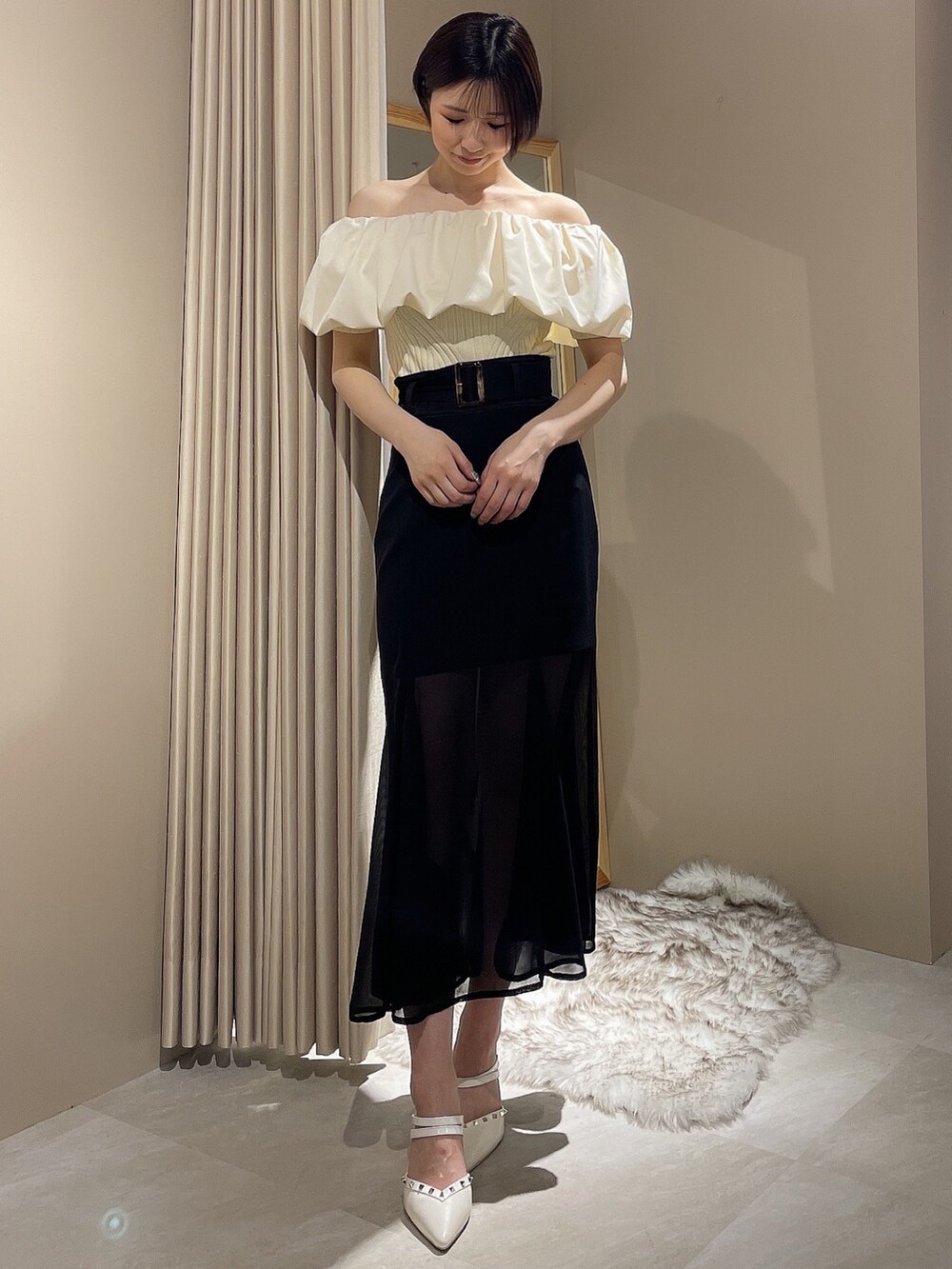 ホワイト系のパンプス、ホワイト系のニット/セーター、ブラック系のスカートを着用したレディースの春コーディネートの2枚目の写真