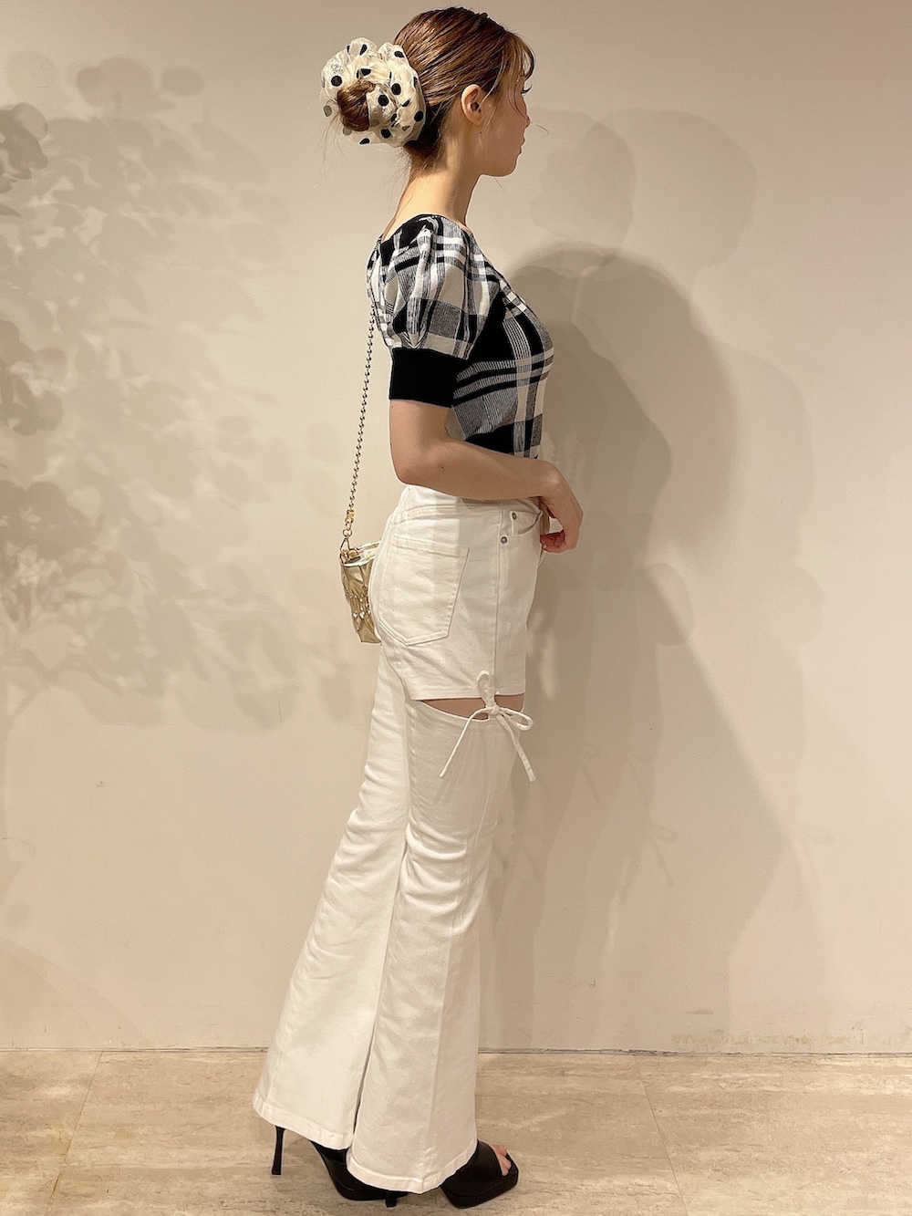 ブラック系のニット/セーター、ホワイト系のデニムパンツ、ゴールド系のハンドバッグを着用したレディースの春コーディネートの3枚目の写真