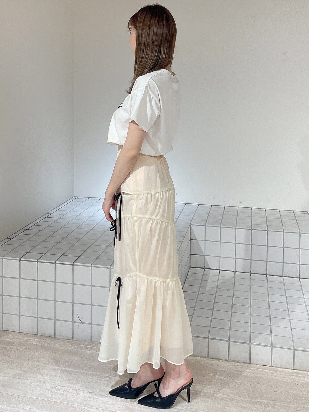 ホワイト系のTシャツ/カットソー、ホワイト系のスカート、ブラック系のパンプスを着用したレディースの夏コーディネートの3枚目の写真