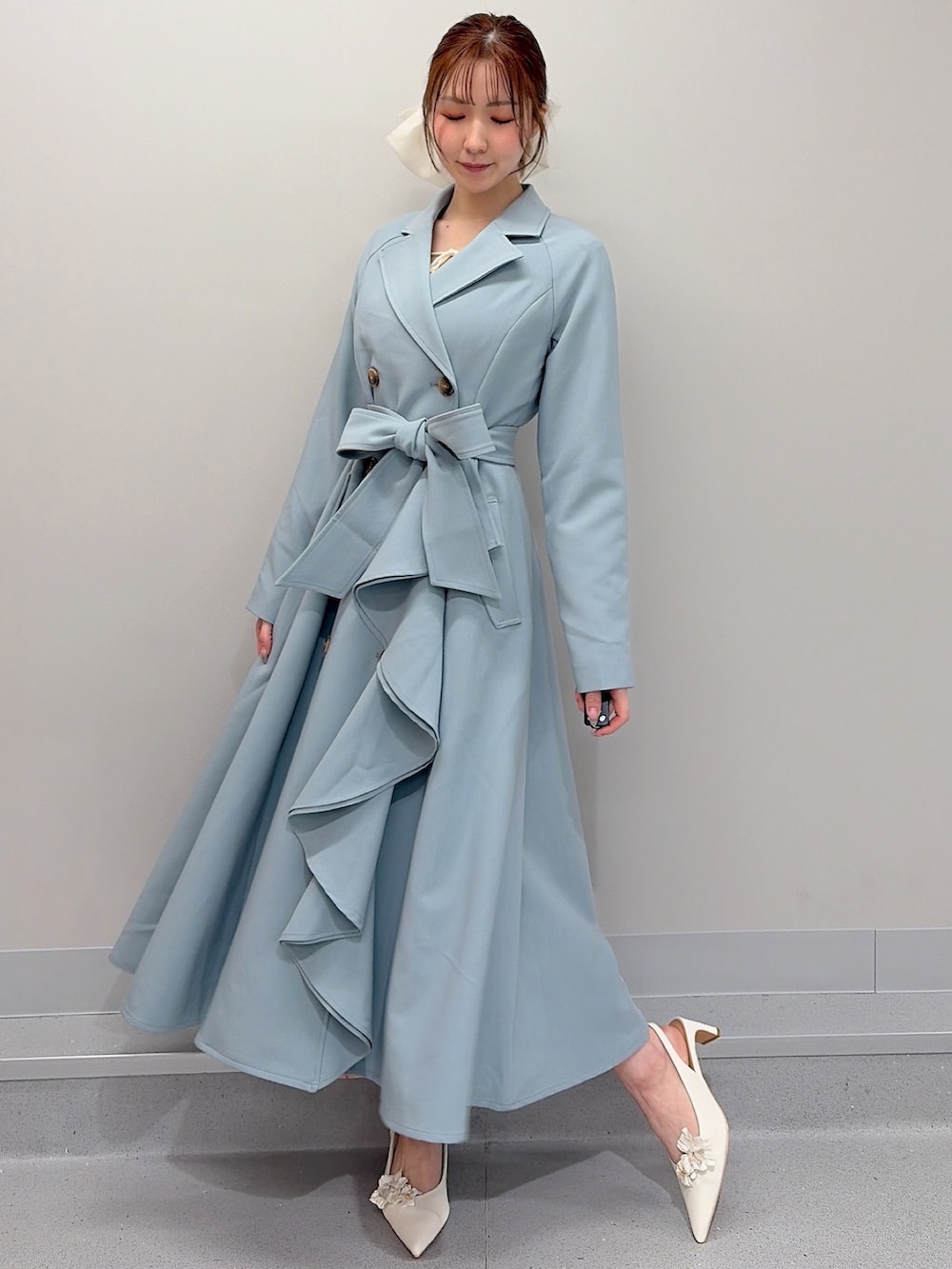 ブルー系のトレンチコート、ホワイト系のパンプス、ホワイト系のバレッタ/ヘアクリップを着用したレディースの冬コーディネートの2枚目の写真