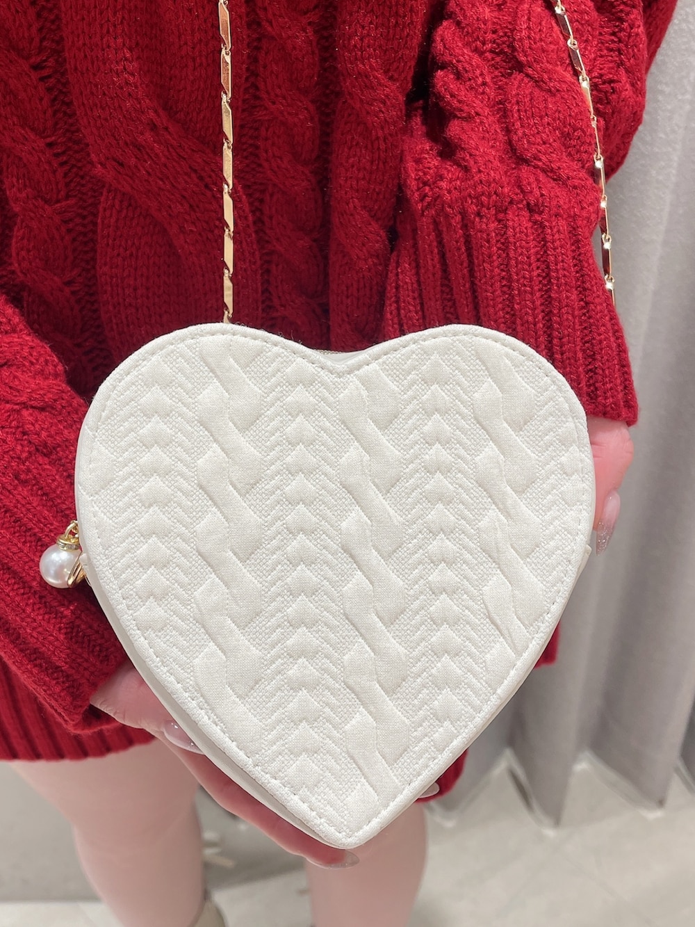 レッド系のニット/セーター、ホワイト系のスカート、ホワイト系のショルダーバッグを着用したレディースの冬コーディネートの8枚目の写真