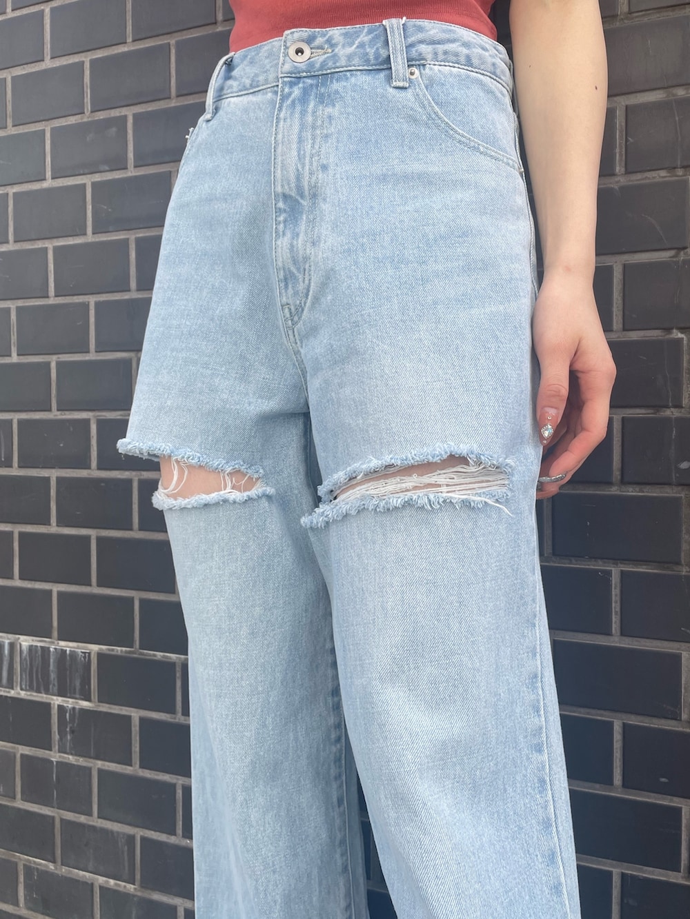 オレンジ系のキャミソール、ブルー系のデニムパンツ、ホワイト系のサンダルを着用したレディースの春コーディネートの7枚目の写真