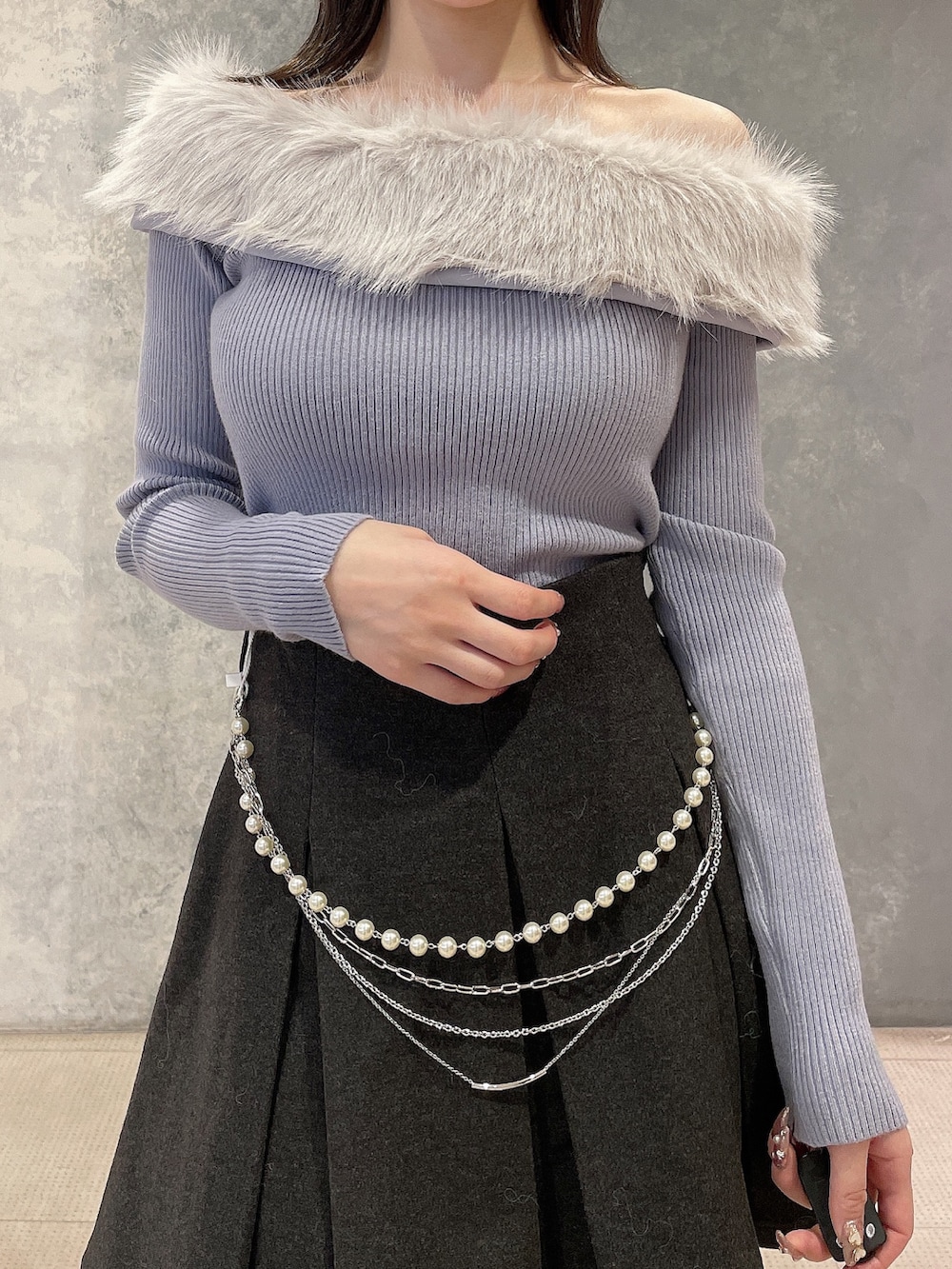 ブルー系のニット/セーター、グレー系のスカート、ブラック系のブーツを着用したレディースの秋コーディネートの4枚目の写真