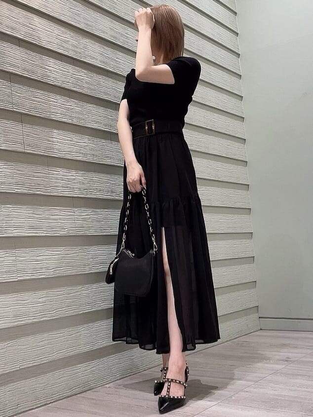 ブラック系のパンプス、ブラック系のニット/セーター、ブラック系のスカートを着用したレディースの春コーディネートの2枚目の写真